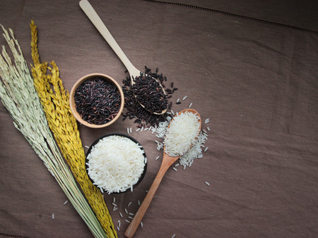 Uncooked Thai Rice,White and brown rice on wooden bowl and spoonの写真素材