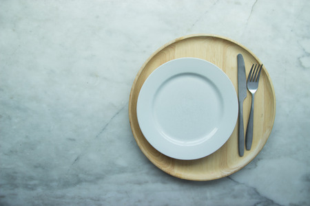 Top view, Closed up empty blank dishware on wooden tray and place on grey granite table. Including fork, knife and spoon.の写真素材
