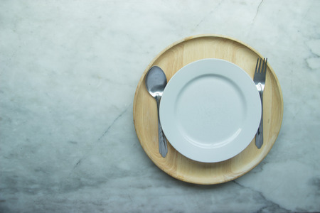 Top view, Closed up empty blank dishware on wooden tray and place on grey granite table. Including fork, knife and spoon.の写真素材