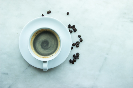 Top View, Closed up hot swirling coffee mug on white plate and cup with heap of coffee's beans on grey granite background.This menu including Espresso, Americano, Latte, Cappuccino, Mocha, Marachino, Macchiato. Made from the best coffee's beans, Arabica. Fresh and tasy.の写真素材