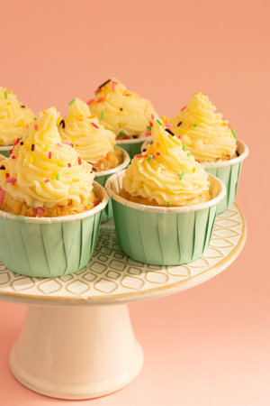 Cupcakes with buttercream frosting and colorful sprinkles on pink background.の写真素材