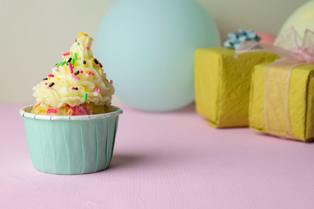 A birthday cupcake with colorful sprinkles and gift box on pink background.の写真素材