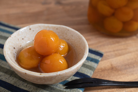 Japanese confectionery, candied kumquats in a small bowl on a wooden table.の写真素材