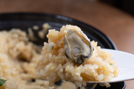 Close up of rice cooked with oysters in a clay pot served on wooden table.の写真素材