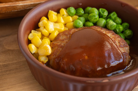 Japanese homemade hamburger steak with demi-glace sauce, steamed sweet corn and green peas.の写真素材