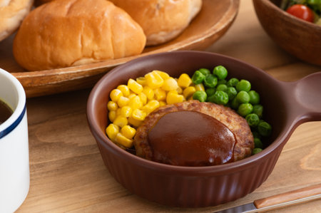 Japanese homemade hamburger steak with demi-glace sauce, steamed corn and green peas.の写真素材