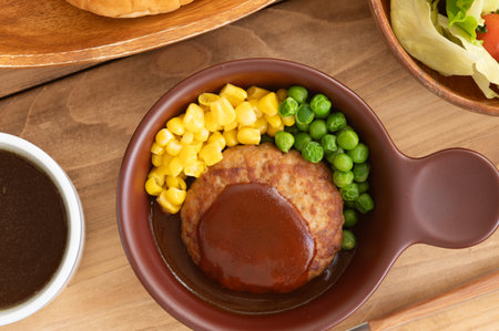 Japanese homemade hamburger steak with demi-glace sauce, steamed corn and green peas.の写真素材