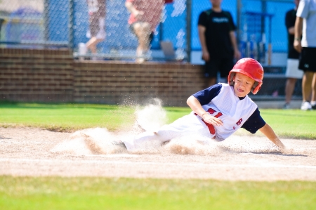 Youth baseball player sliding in at home の写真素材