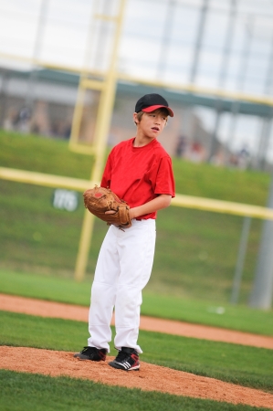 Young baseball player looking at the batter.の写真素材