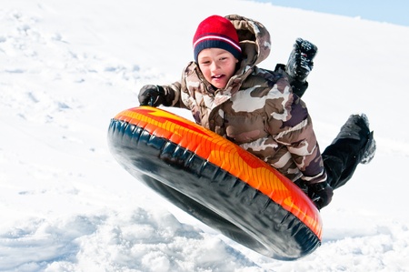 A happy boy up in the air on a tube sleding in the snow の写真素材