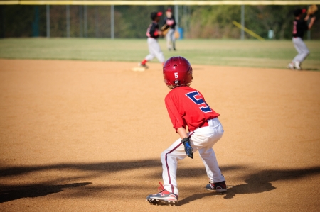 Little league baseball player looking to steal second base.