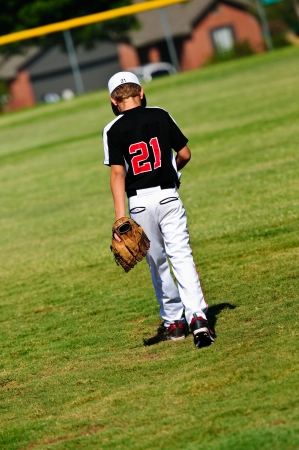 Youth baseball player walking onto the field to get ready to play.の写真素材