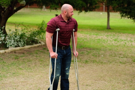 Muscular bald man on crutches outdoors.の写真素材