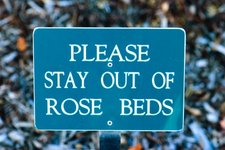 Sign that says Please stay out of rose beds.のeditorial素材