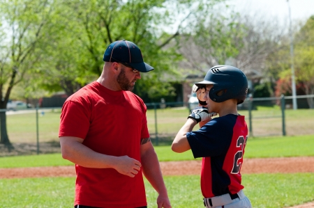 Baseball coach giving instruction to teen baseball boy.の写真素材