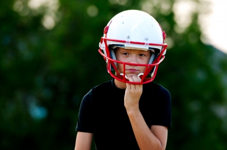 Young football boy in helmet with sad look on face.の写真素材