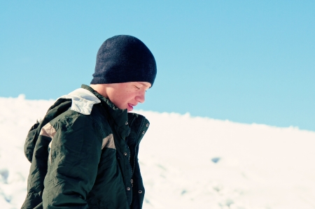 teen boy walking in snow looking sadの写真素材