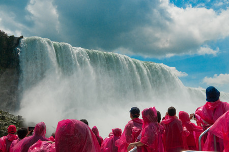 Tourist in rain coats looking up at Niagara Falls, Ontario, Canadaの写真素材