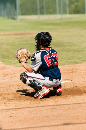 Young teen baseball player catching during game behind the plateの写真素材