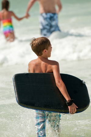 Young boy going out into the ocean to body surf and boogie board.の写真素材