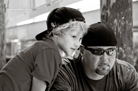 Adorable son and handsome father with backwards hats looking cool in black and white.の写真素材