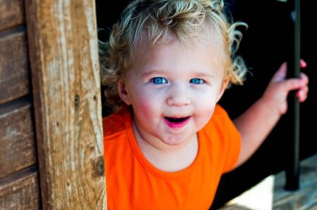 Close up of curly blonde haired toddler girl behind bars at a pumpkin festival.の写真素材