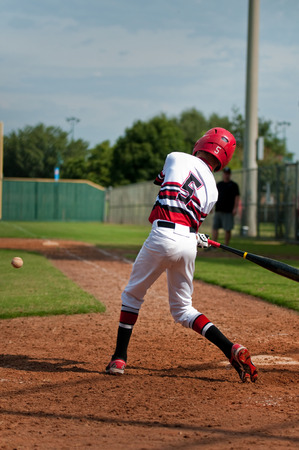 Little league baseball player swinging bat to hit the ball.の写真素材