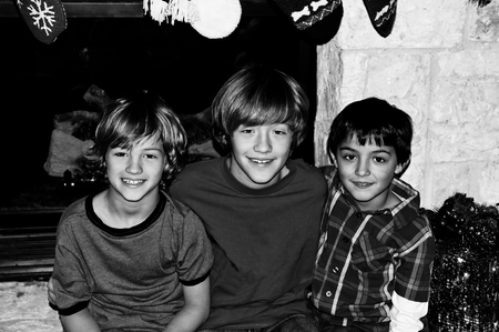 Indoor black and white portrait of three cute boys in front of fireplace for the holidays.の写真素材