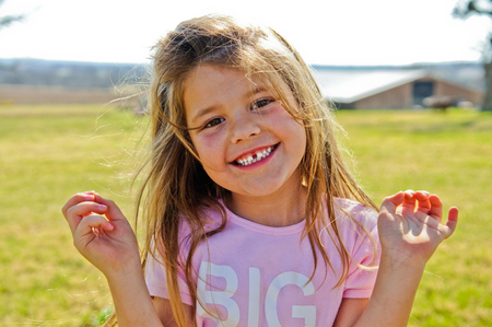Happy retty little girl outside with barn in background.の写真素材