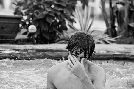 Teen boy in swimming pool sad and crying with hands on eyes.の写真素材
