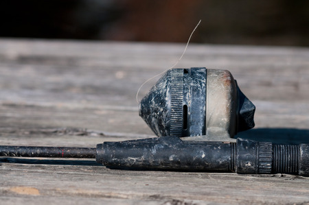 Old fishing pole and rod laying on wooden bridgeの写真素材