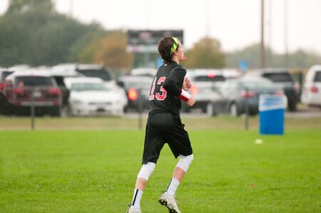 Young athlete playing 7 on 7 football with gloves and headband.
