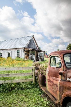 Old rustic American truck in front of an old abandoned farm houseの写真素材