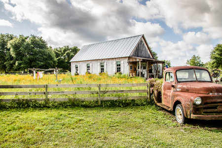 Old rusty car in a rural setting with a barn in the backgroundの写真素材