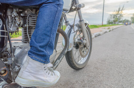 Someone bestride old motorcycle parking on the roadside in eveningの写真素材