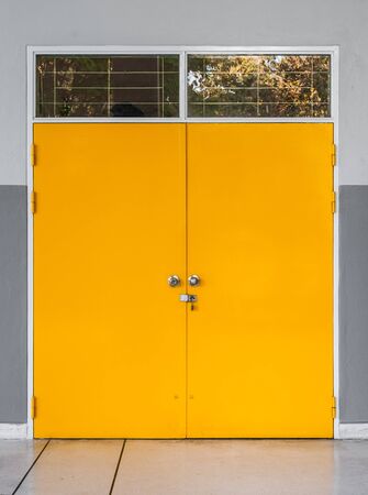 Closeup to Locked Yellow Metal Door with Glass Windowの写真素材