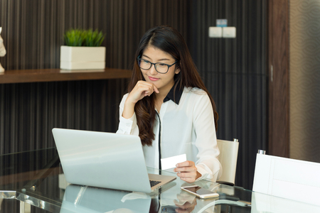 An asian business woman using a credit card in front of a laptopの写真素材