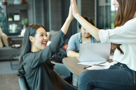 Teamwork of Asian business people giving high five, tag teamの写真素材