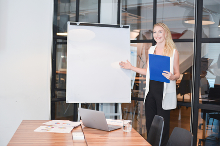 Business blonde woman presenting a project on blank whiteboardの写真素材