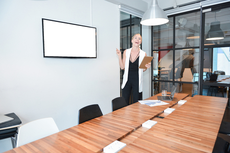 Business blonde woman presenting a project on blank screen TVの写真素材