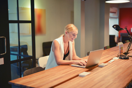 Business blonde girl using a laptop in an officeの写真素材