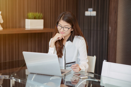 An Asian business woman using a credit card in front of a laptopの写真素材