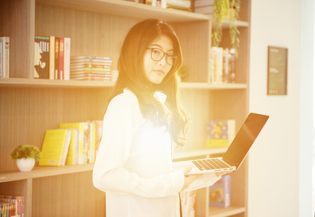 Business Asian girl leaning and using a laptop in libraryの写真素材