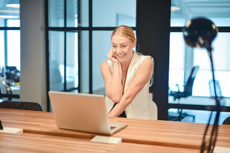 Happy business blonde girl using a laptop in an officeの写真素材