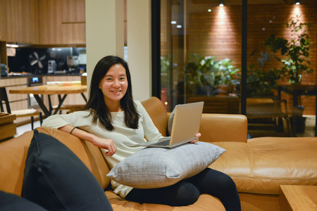 Business woman using a laptop in living room at nightの写真素材