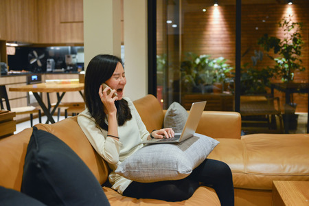 Business woman using a smartphone in living room at nightの写真素材