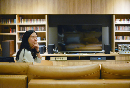 Asian woman yawning in front of blank screen TV in living room at nightの写真素材