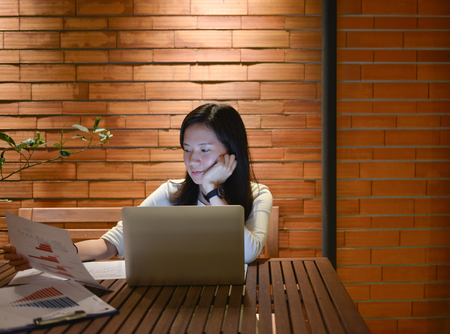 Stressed Asian woman using laptop at night, freelance working lateの写真素材