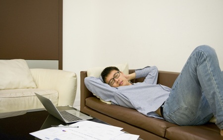 Asian businessman sleeping on sofa in living room at nightの写真素材