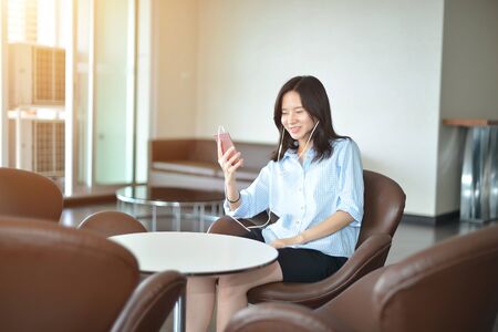 Happy business woman talking on the phone in living roomの写真素材